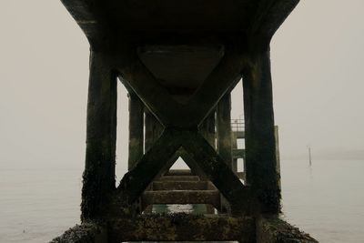 Below bridge over sea against sky during sunset