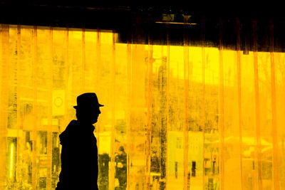 Silhouette man standing against yellow window