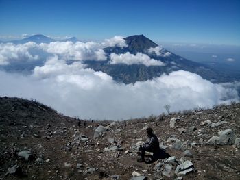 Side view of man sitting on mountain 