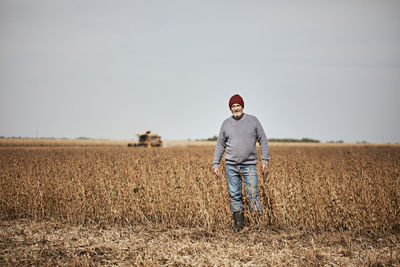 Farmer standing in soybean farm against clear sky