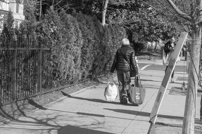 Rear view of man walking on footpath by street