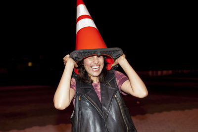 Portrait of young woman in hat standing at night