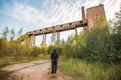 Rear view of man walking on road against sky