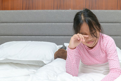 Rear view of woman sitting on bed