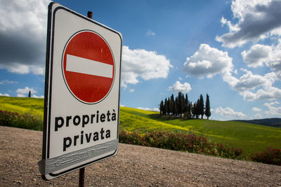 Information sign on field against sky