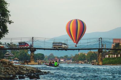 Hot air balloon flying over river against sky