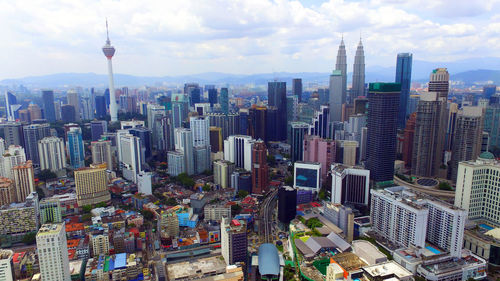 Aerial view of city buildings against cloudy sky