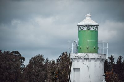 Water tower by lighthouse against sky