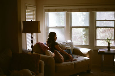 Woman sitting on sofa at home in window light