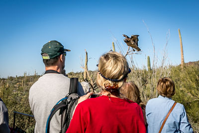 Rear view of friends flying against clear sky