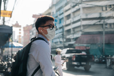 Man wearing protective mask while standing on street in city