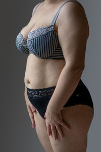 Midsection of woman standing against black background