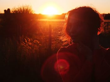 Young woman standing on field during sunset