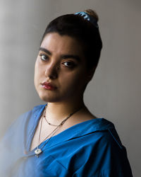 Portrait of young woman standing against wall