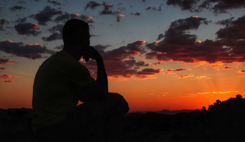 Silhouette man against orange sky during sunset