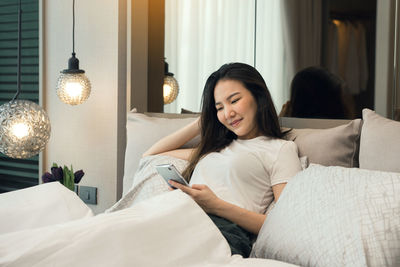 Portrait of young woman sitting on bed at home