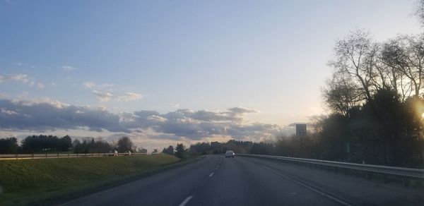 Road by trees against sky