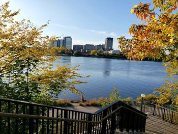Scenic view of river by buildings against sky during autumn