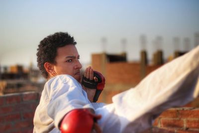 Young man practicing karate against sky