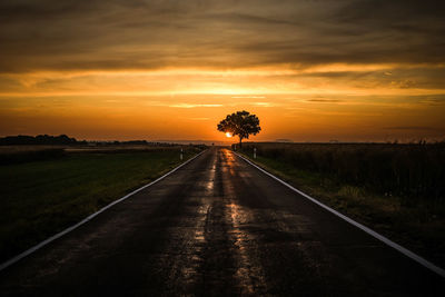 Road amidst trees against sky during sunset