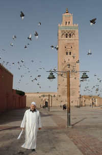 Full length of man flying birds against sky