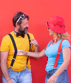 Fashionable mature couple standing against red wall