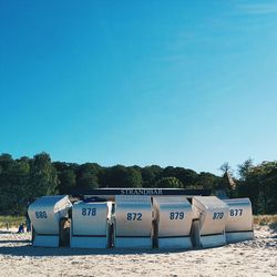 Hooded chairs on beach against clear blue sky