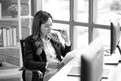 Young woman using mobile phone while sitting on table