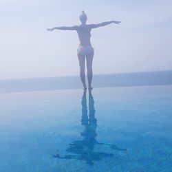 Full length of woman standing at sea shore against sky