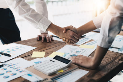 Midsection of business colleagues shaking hands in office