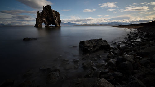 Rocks on sea shore against sky during sunset