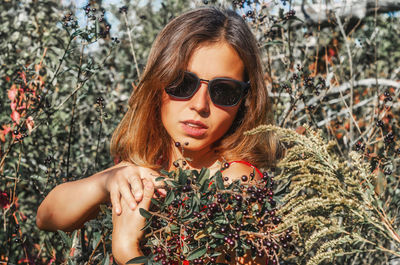 Pretty woman in sunglasses with branches with black berries in her hands.