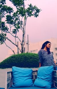 Woman sitting on seat against clear sky