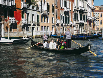 People on boat in canal along buildings