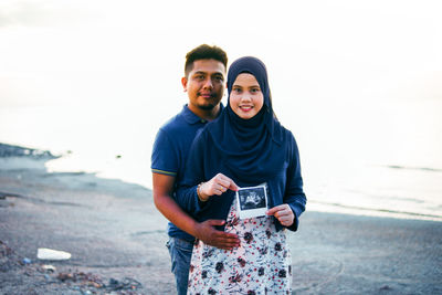 Portrait of young couple standing on beach