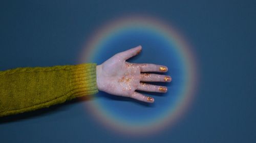 Close-up of shiny hand over blue background