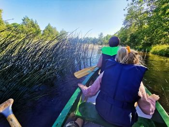 Rear view of people sitting on boat against trees