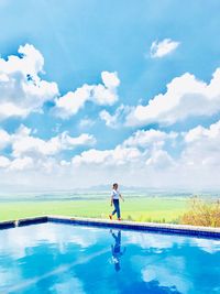 Man standing in swimming pool against sky