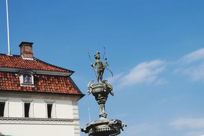 Low angle view of statue against building against blue sky