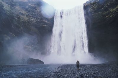 Rear view of man standing by waterfall