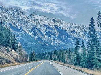 Road amidst snowcapped mountains against sky
