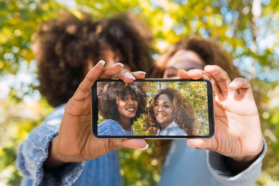 Positive afro black friends in a fun mood taking selfie with smartphone using the front camera