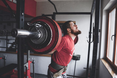 Man lifting barbell while exercising at gym