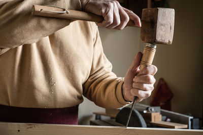 Midsection of carpenter using hammer in workshop