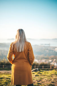 Rear view of woman looking at sea shore against sky