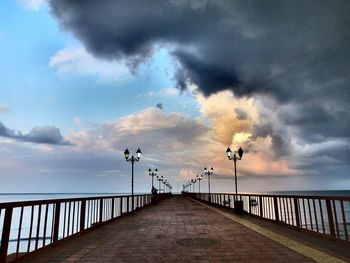 Pier on sea against cloudy sky