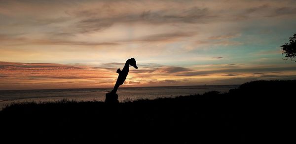 Silhouette seahorse on field against sky during sunrise 