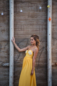 Young woman looking down while standing against brick wall