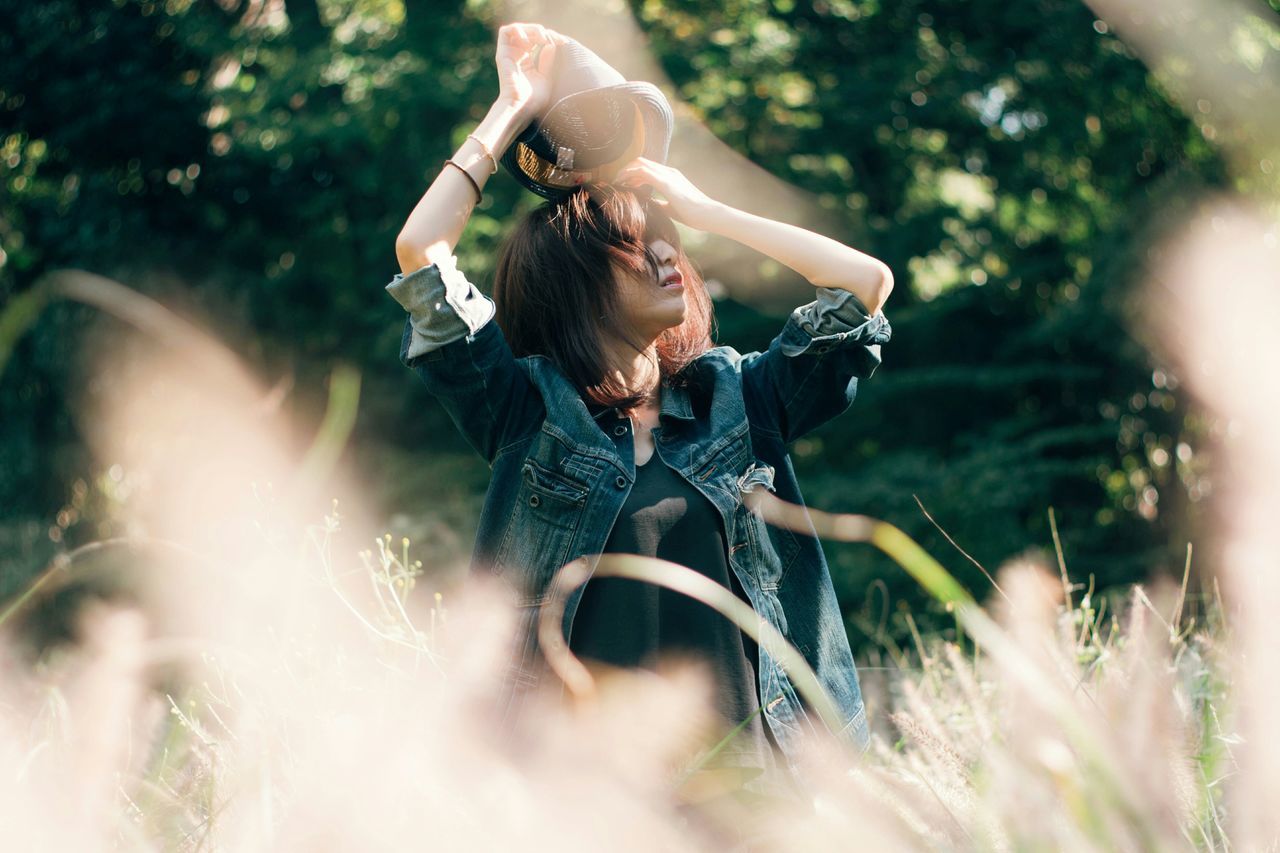 lifestyles, leisure activity, sunlight, casual clothing, person, long hair, plant, playing, enjoyment, nature, selective focus, day, focus on foreground, outdoors, young adult, weekend activities, beauty, contemplation, freshness