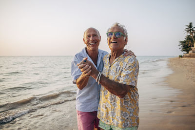 Happy elderly gay couple dancing on beach at ko lanta island